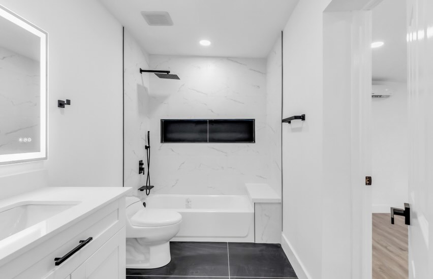 Completed white and black bathroom with marble-look walls and a modern soaking tub