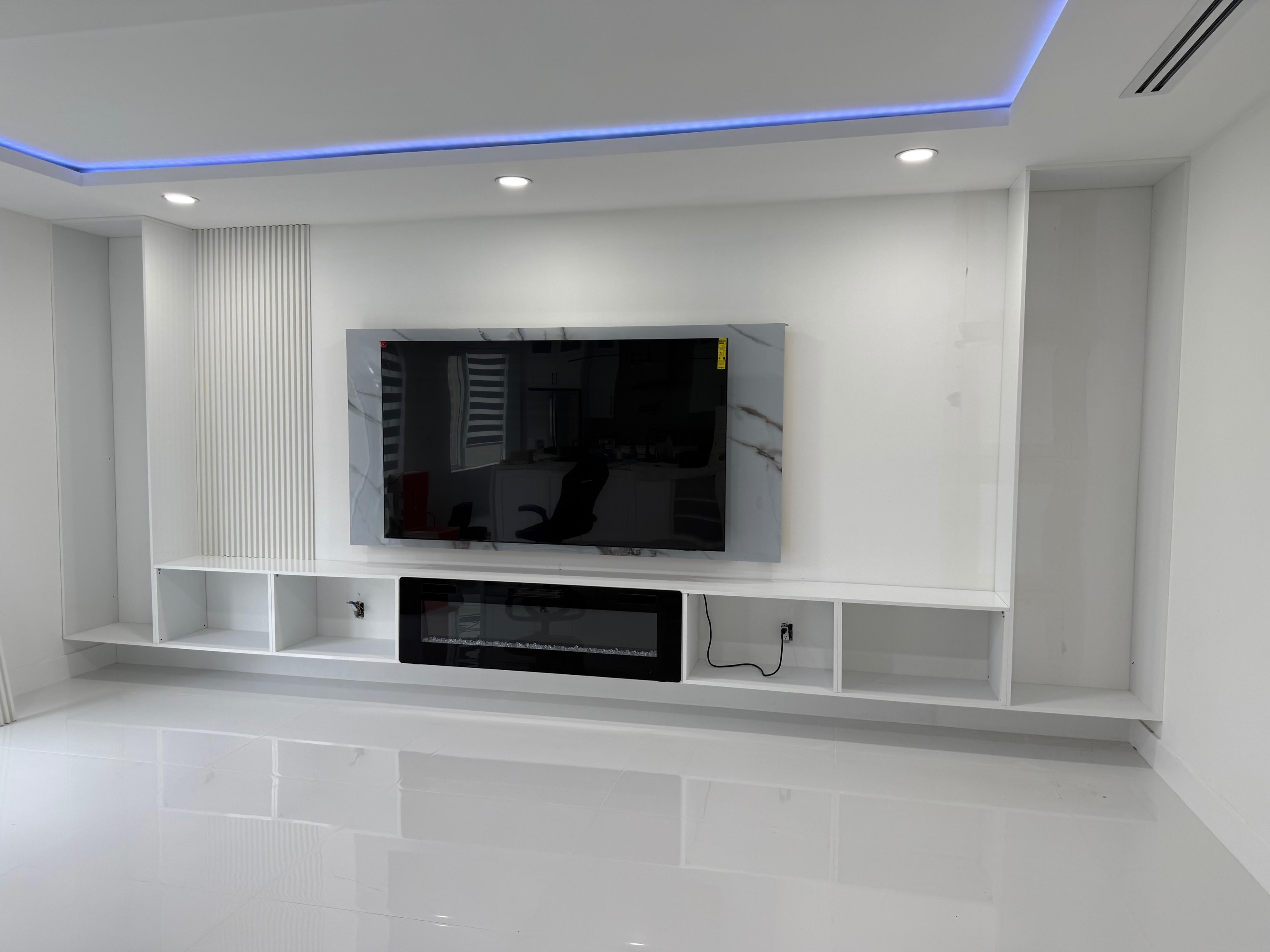 Completed white built-in media wall with shelving and an electric fireplace