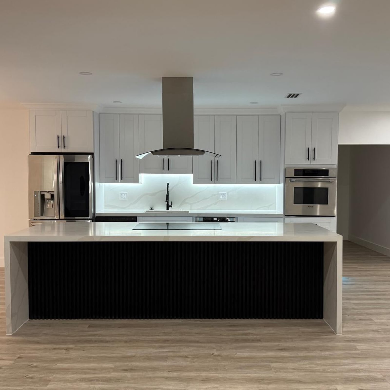 Completed modern kitchen with a black fluted island and illuminated backsplash