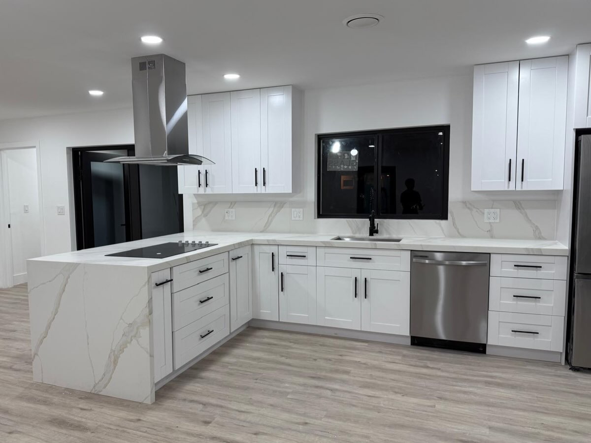 Completed open-plan white kitchen with peninsula, marble-look surfaces, and black accents