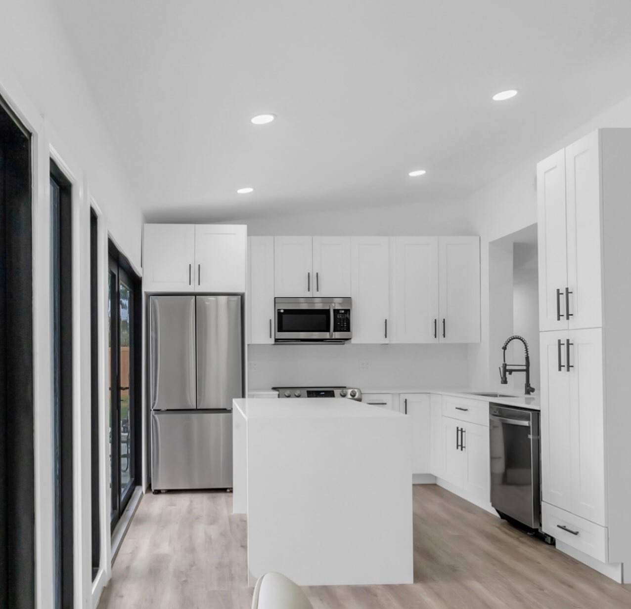 Completed bright white kitchen with shaker cabinetry and a waterfall island
